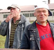Zwei Männer rauchend vor einem landwirtschaftlichen Gebäude